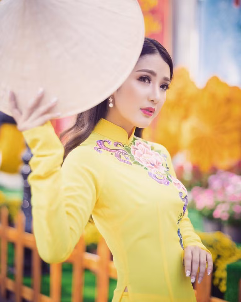 Linh Napie diện áo dài sắc vàng tươi với những họa tiết vẽ đầy sắc xuân.