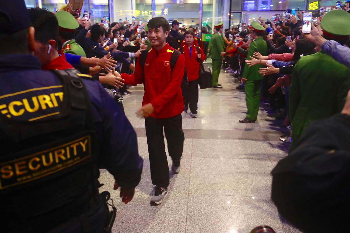 Bùi Tiến Dũng tươi cười bắt tay NHM ở sân bay.