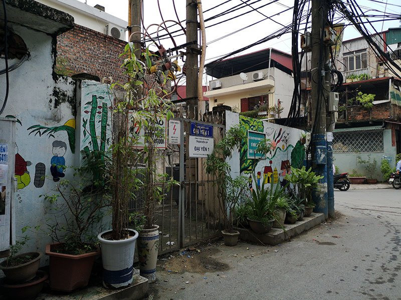 Bích họa cùng các chậu cây cảnh bao quanh trạm điện trong ngõ 173 phố Hoàng Hoa Thám (Ba Đình, Hà Nội) che khuất một phần tấm biển cảnh báo nguy hiểm.