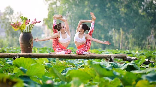 Không áo dài, áo yếm, hai người phụ nữ xinh đẹp đã quyết định chọn cho mình trang phục thoải mái để thực hiện những động tác yoga đẹp mắt. Sự kết hợp giữa những động tác uốn dẻo với nền xanh ngát của đầm sen đã tạo ra những khoảnh khắc vô cùng đẹp.