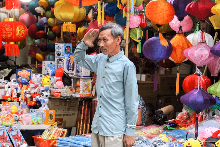 Người bán hàng tranh thủ tạo dáng để các bạn trẻ chụp ảnh.