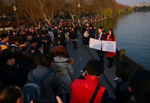 Hai cô gái trẻ xinh đẹp này cầm hai tấm biển ghi "Muốn hẹn em hãy đến đây. Em chờ anh!" và "Mau tới đây thuê em làm người yêu của anh".