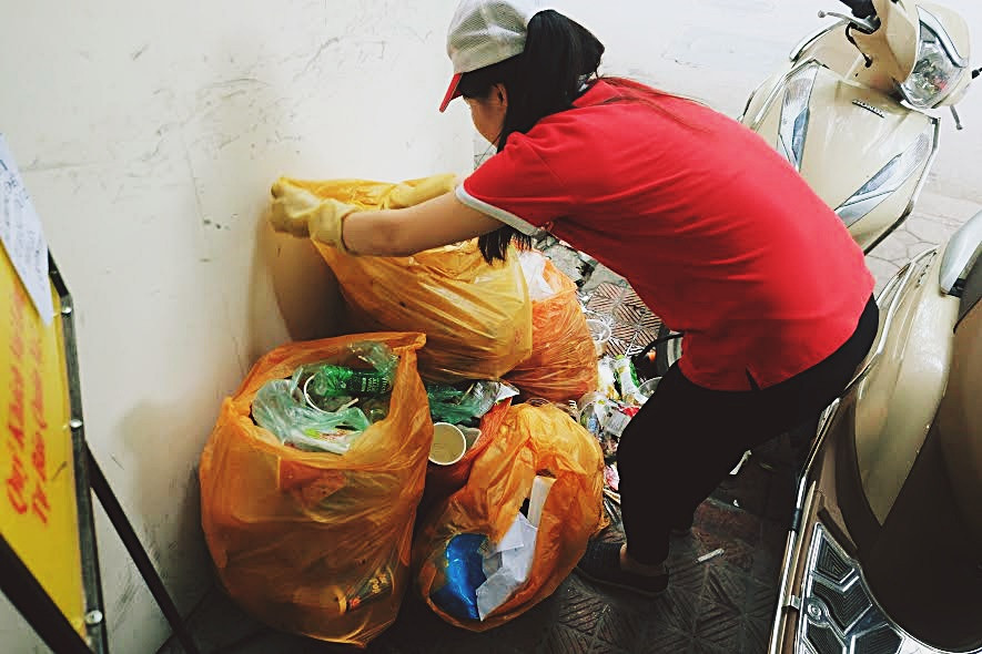 Nhân viên vất vả thu rác thải tại cửa hàng tiện ích.