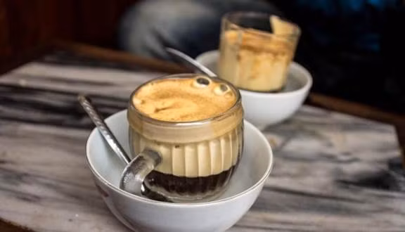 Giữa không gian nho nhỏ thân thuộc của quán cà phê cũ đã nhuốm màu thời gian, người ta dễ thấy mình như bé lại, mọi suy nghĩ cũng chậm rãi thong thả hơn nhiều. Cà phê ấm nóng, ngòn ngọt lại beo béo, vừa nhâm nhi vừa nhìn về hồ Gươm phía dưới, đủ để xoa dịu mọi nỗi niềm còn băn khoăn.