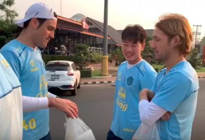 Tiền vệ Lương Xuân Trường thoải mái ngồi lề đường ăn cơm nắm và thịt xiên cùng các đồng đội.
