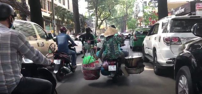 Người phụ nữ bán hàng rong này gánh trên vai chiếc bếp than đỏ rực cùng nồi nước dùng sôi sùng sục, nghi ngút khói.