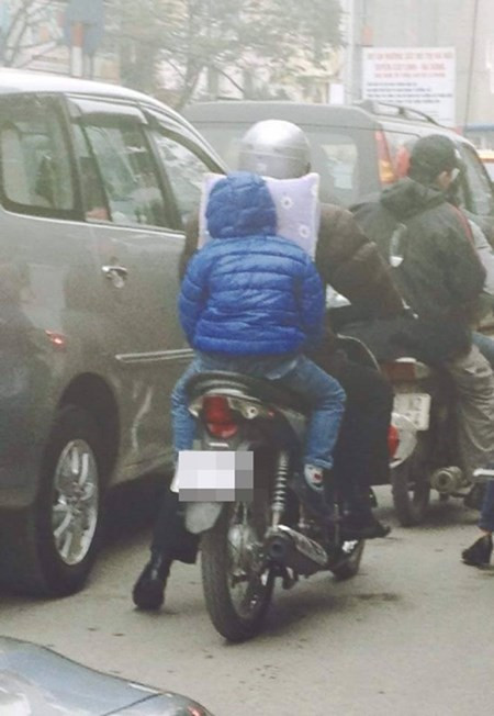 Đứa trẻ đặt gối đầu vào lưng bố, ngủ ngon lành khi đang đi trên đường.