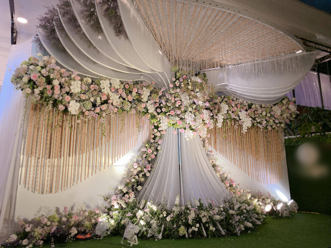 Tiệc cưới của cặp đôi Rich Kid lấy tông trắng làm chủ đạo, bài trí theo phong cách lãng mạn cổ điển. Góc chụp ảnh lộng lẫy không kém được đặt ngoài sảnh là nơi cô dâu chú rể chụp ảnh kỷ niệm cùng khách mời