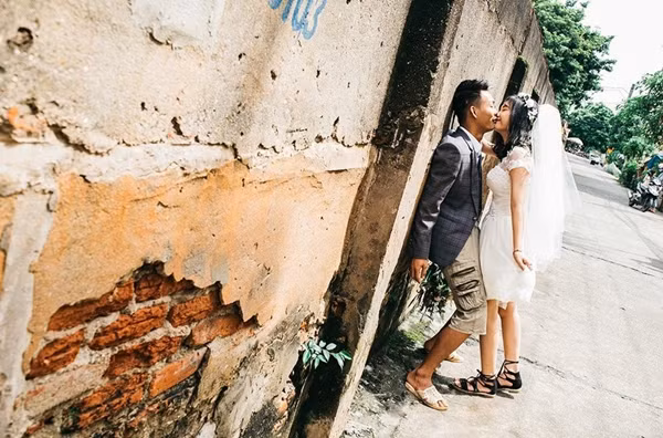 Với sự đơn giản hóa đến mức tối đa cho những bức ảnh cưới của mình, cặp đôi đến từ Phú Thọ trên đã không chọn cho mình những váy vóc xa xỉ cũng không lựa chọn địa điểm sang trọng như trong các bộ phim truyền hình, Văn Hưng và Phương Uyên chỉ đơn giản là đứng chụp ảnh ở ngay bờ tường, góc chợ.