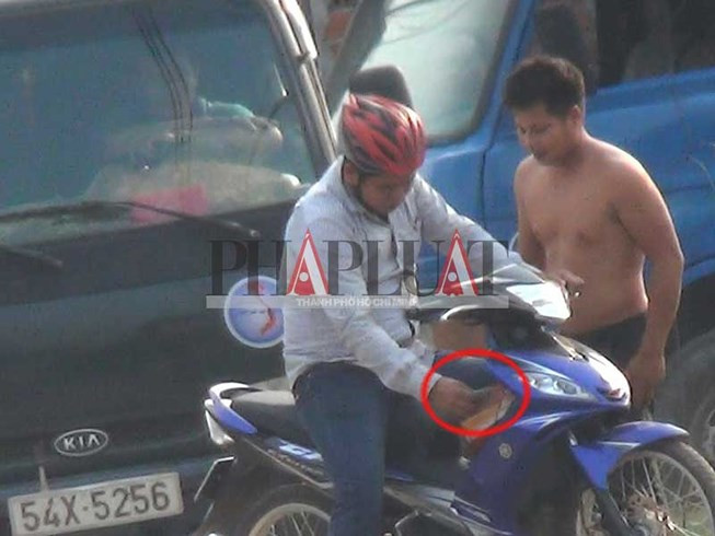 Công an viên Đặng Minh Tâm nhận tiền của ông Siêu rồi phóng xe đi. Ảnh: N.TÂN (Ảnh cắt từ clip)