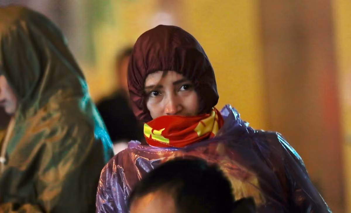 Một CĐV nữ chùm kín áo mưa, áo gió để cổ vũ cho đội tuyển Việt Nam.