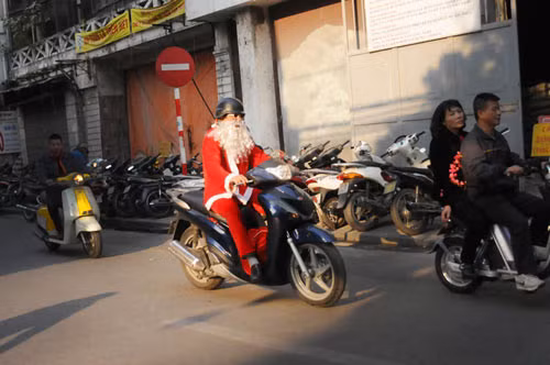 Trước đó, tại Việt Nam cũng xuất hiện rất nhiều ông già Noel làm nhiệm vụ giao quà trong dịp Giáng sinh. Ông Thái Duy Anh ( 57 tuổi) tại Hà Nội, dù bận trăm công ngàn việc nhưng vẫn tranh thủ dành thời gian tới hàng Mã - nơi có cửa hàng bán đồ trang trí của con gái để nhận các món quà chuẩn bị đi phát cho các em nhỏ. Ảnh: Dân Việt.