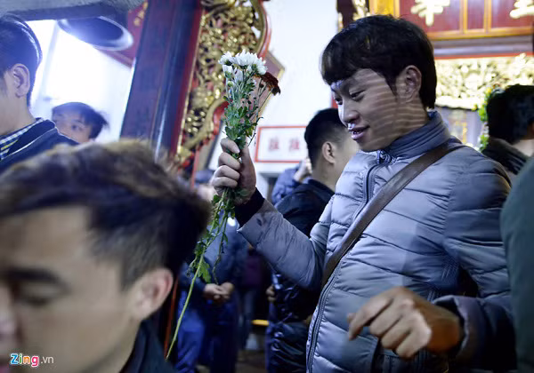 Ngoài đền Trần, nhiều người chưa vào được bên trong đã trèo tường, trèo cây. Phía bên trong, du khách ùn ùn kéo vào đền dùng tiền, sớ xoa vào bảo kiếm, chuông đồng để cầu tài lộc. Ảnh: Zing.vn