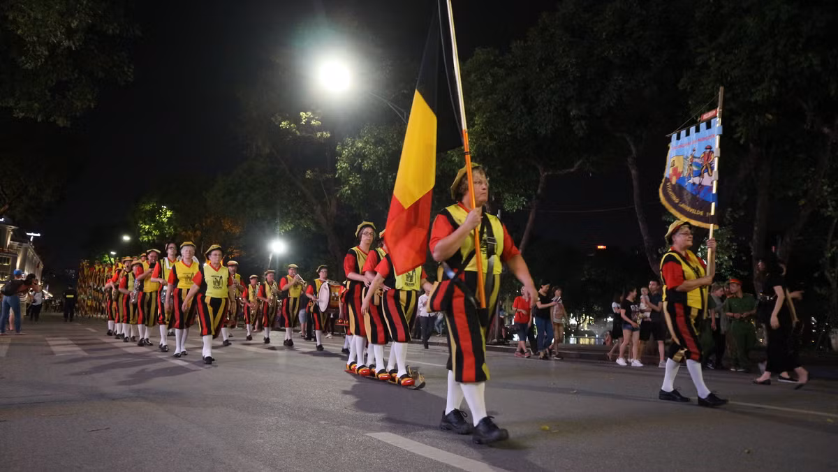 Đoàn diễu hành của Vương quốc Bỉ bao gồm Quốc kì, cờ Hoàng gia Bỉ, đoàn quân nhạc và đội cà kheo.