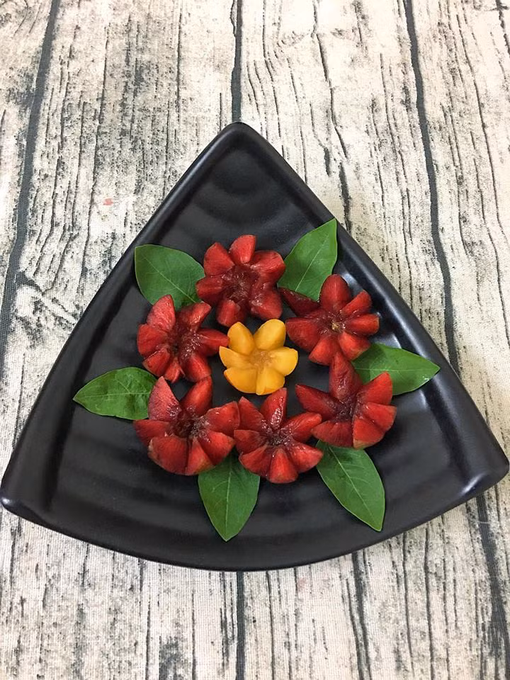 Chỉ với hai loại mận là mận vàng và mận đỏ, kết hợp với những chiếc đĩa hình thù khác nhau, bạn đã có những "bức tranh hoa mận" mang nét độc đáo riêng. Để tỉa mận thành hoa sáu cánh, bạn khía mận theo 12 đường gấp khúc rồi vặn tròn để tách hai phần. Khi bỏ hạt, phần mận được tỉa cũng xòe ra khiến bạn có cảm giác quả mận trở nên to hơn, nhìn rất thích mắt.