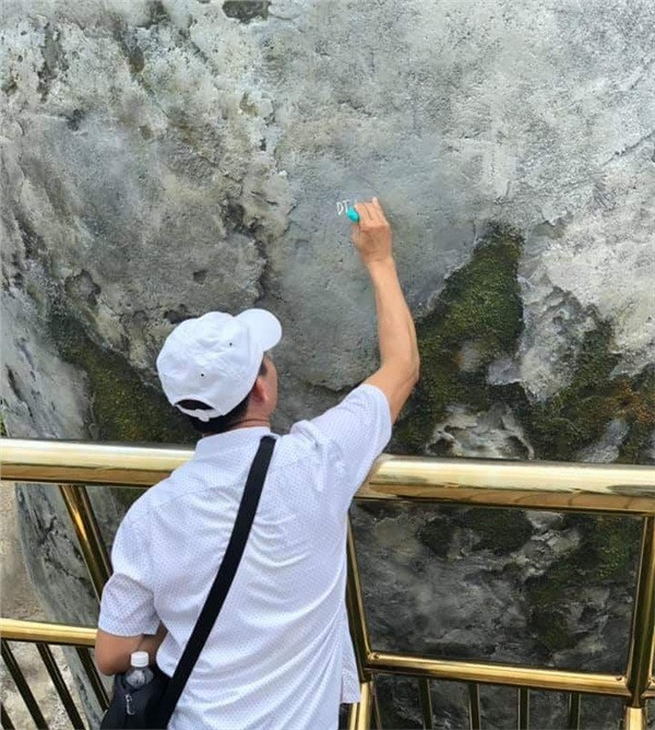 Hình ảnh được chia sẻ cho thấy người đàn ông hồn nhiên viết chữ lên bàn tay khổng lồ ở cầu Vàng. Mặc cho hành động của mình được những du khách khác ghi lại, người đàn ông này vẫn tập trung hết công suất để hoàn thành công cuộc vẽ bậy.