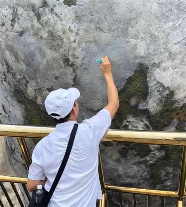 Hình ảnh được chia sẻ cho thấy người đàn ông hồn nhiên viết chữ lên bàn tay khổng lồ ở cầu Vàng. Mặc cho hành động của mình được những du khách khác ghi lại, người đàn ông này vẫn tập trung hết công suất để hoàn thành công cuộc vẽ bậy.