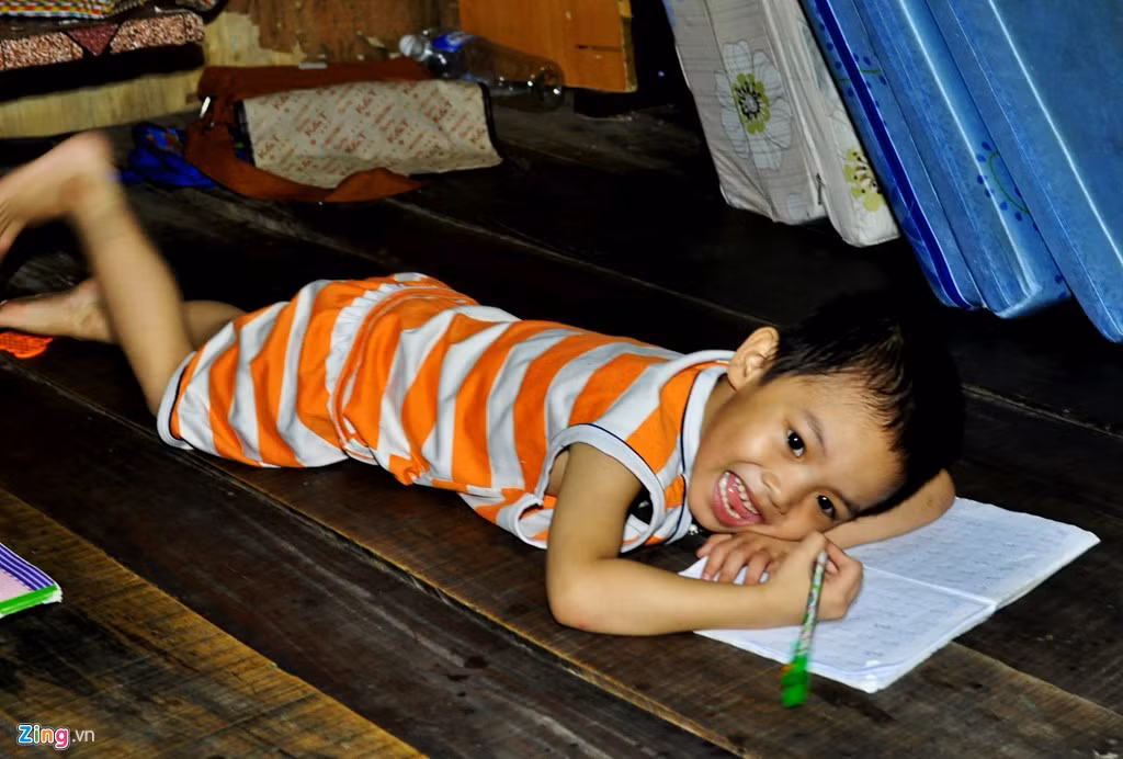 Bé trai Phạm Viết Tú (5 tuổi) nằm dài dưới sàn nhà căn lều viết bài.