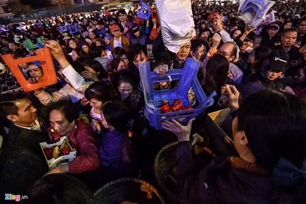 Khoảng 18h, khu vực bên ngoài đình Phúc Khánh đông nghịt người đến làm lễ. Nhiều người còn trèo qua hàng rào an ninh bất chấp lực lượng an ninh có mặt tại đây. Tại đây đã xảy tình trạng chen lấn, giành từng quả chuối hay oản phát lộc. Cảnh tượng chen chúc phản cảm vẫn diễn ra dù những người phát lễ liên tục nhắc nhở mọi người. Nhiều người không chen chân được vào trong đành ngồi từ xa vái vọng. Ảnh: Zing.vn