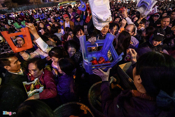 Khoảng 18h, khu vực bên ngoài đình Phúc Khánh đông nghịt người đến làm lễ. Nhiều người còn trèo qua hàng rào an ninh bất chấp lực lượng an ninh có mặt tại đây. Tại đây đã xảy tình trạng chen lấn, giành từng quả chuối hay oản phát lộc. Cảnh tượng chen chúc phản cảm vẫn diễn ra dù những người phát lễ liên tục nhắc nhở mọi người. Nhiều người không chen chân được vào trong đành ngồi từ xa vái vọng. Ảnh: Zing.vn