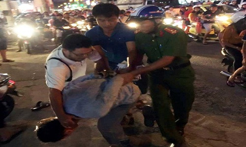 Thanh niên chặn ôtô bẻ gương chiếu hậu bị người dân, công an khống chế. Ảnh: B.H.Y.