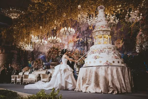 Chiếc bánh cưới cao gần 4 mét màu trắng kem điểm hoa là điểm nhấn đặc biệt trên sân khấu của đám cưới "thần tiên" này.