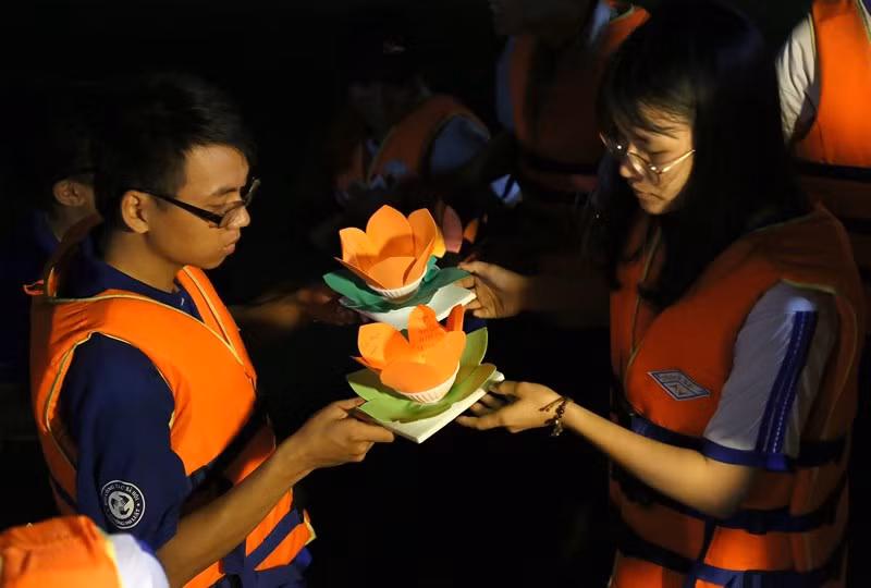 Các tình nguyện viên tiếp nhận hoa đăng và hỗ trợ người dân thả hoa đăng xuống sông Sài Gòn.
