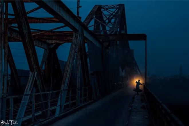 Sáng sớm mờ sương tại cầu Long Biên, những xe hàng hoa quả nhộn nhịp tấp nập dỡ hàng. Hình ảnh con người với quang gánh nặng trĩu trên vai để đưa hoa quả tới những chợ nhỏ trở nên vô cùng ấn tượng. Ảnh: Đinh Tuấn.