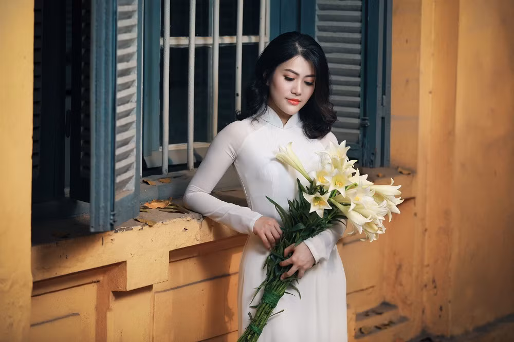 Trong tà áo dài trắng, bà mẹ bỉm sữa Thu Phương trang điểm đơn giản, ôm bó hoa vào lòng và nở nụ cười tươi. Gương mặt thanh tú, ánh mắt trong veo, vẻ đẹp dịu dàng của chị nhanh chóng ghi điểm trong lòng của nhiều người.