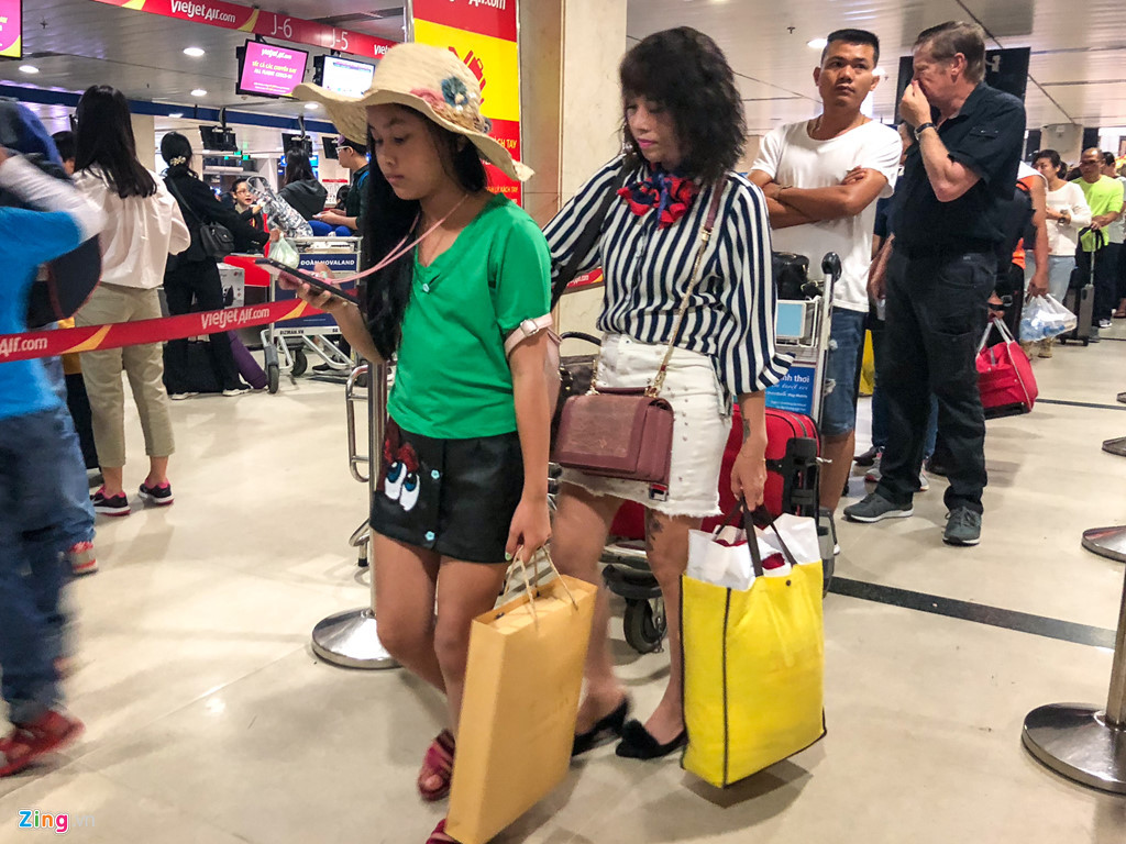 Tại quầy làm thủ tục của một hãng hàng không, từng hàng dài hành khách chờ làm thủ tục. Vào dịp nghỉ lễ này, du lịch là lựa chọn khá phổ biến của người dân thành phố. Trong ảnh, một bé gái đã chuẩn bị sẵn nón để đi biển cùng mẹ.