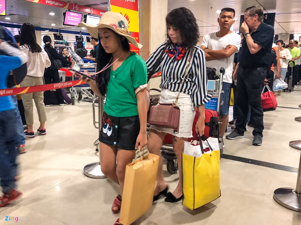 Tại quầy làm thủ tục của một hãng hàng không, từng hàng dài hành khách chờ làm thủ tục. Vào dịp nghỉ lễ này, du lịch là lựa chọn khá phổ biến của người dân thành phố. Trong ảnh, một bé gái đã chuẩn bị sẵn nón để đi biển cùng mẹ.