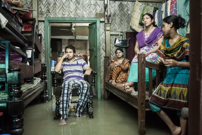 Cuộc sống trong nước triều dâng ở thành phố Chittagong, Bangladesh. Một gia đình đang ngồi xem tivi trong căn nhà ngập nước triều cường ở Chittagong. Khi mực nước biển dâng cao, cuộc sống của 6,5 triệu dân trong thành phố sẽ bị ảnh hưởng nghiêm trọng. Ảnh: Jashim Salam.