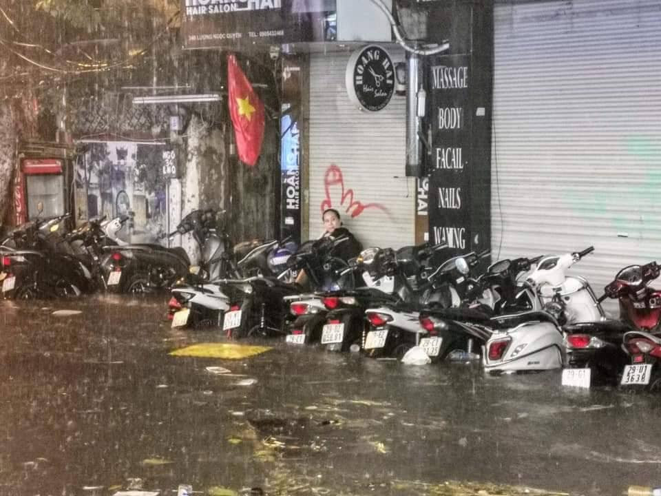 Mưa khiến rác thải tràn về khu trũng và miệng cống nên nhiều chủ cửa hàng phải vất vả dọn dẹp và che chắn.