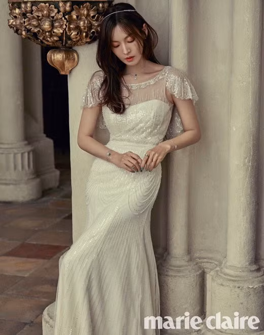 Cô dâu U40 Kim So Yeon xinh như nữ thần trong bộ váy cưới có thiết kế vai áo rủ, những đường xếp nếp ở chân váy và chất liệu vải bóng giúp cô càng thêm nổi bật.