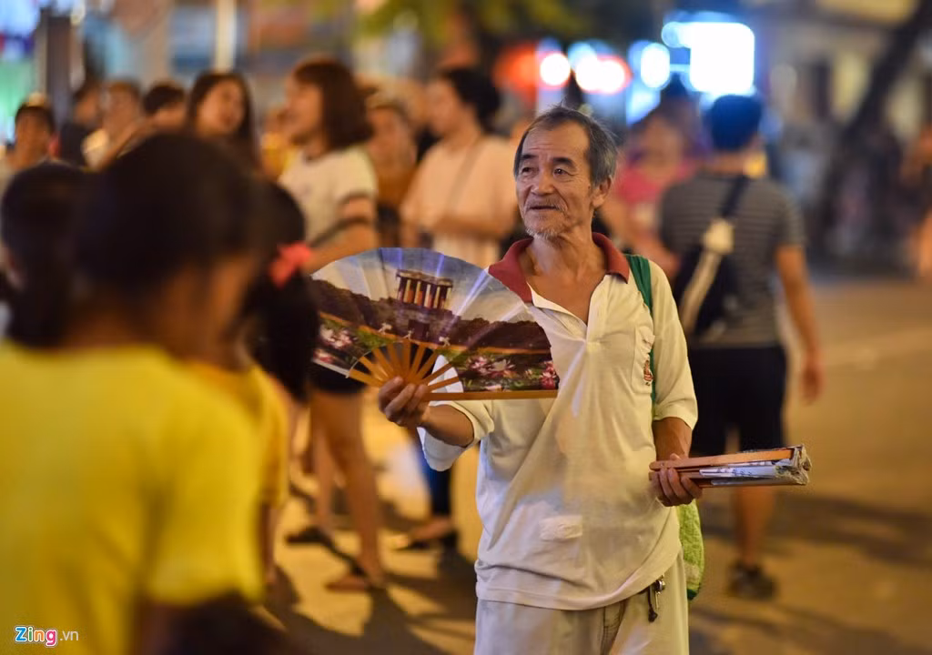 Một ông cụ bán quạt trên phố Hàng Bài liên tục chèo kéo khách.