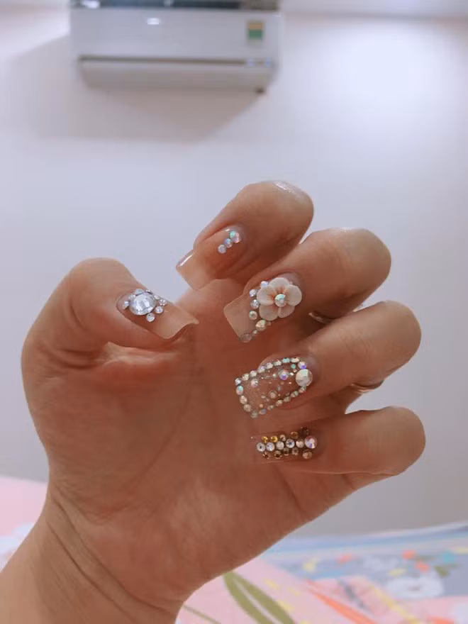 Theo chia sẻ của Angela Do, bộ nail cô làm tại một cửa hàng trong chợ trông cũng bình thường, không phải sang trọng lắm, loại đá gắn trên móng cũng không phải loại xịn như chủ tiệm quảng cáo, không sáng như khi chụp lên hình, khi tính tiền thì giá cắt cổ: 2050 nghìn cho bộ móng.