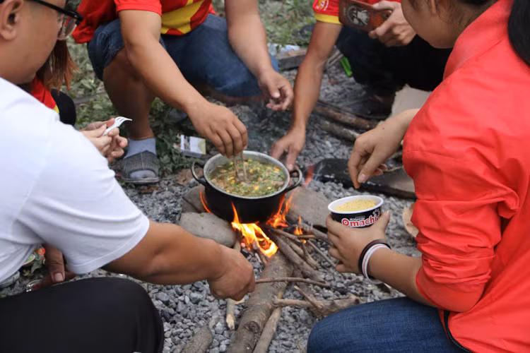 Trong lúc khó khăn khi lương thực trên xe chỉ là những cốc mì, các CĐV Việt Nam đã phải sử dụng đến "bản năng sinh tồn" của mình. Một bếp ăn "dã chiến" đã được lập lên ngay giữa rừng núi đại ngàn của nước bạn Lào.