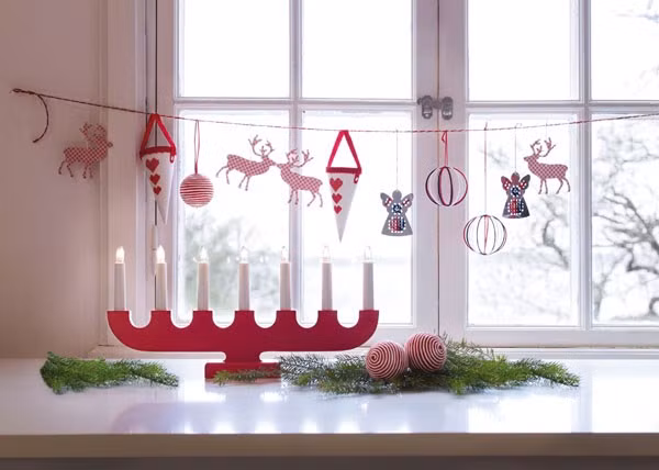 Cửa sổ phòng khách thường được thiết kế khá lớn nhằm đón nhận nhiều ánh sáng vào phòng. Đây cũng chính là vị trí thích hợp để trang trí trong nhà mỗi mùa lễ Giáng sinh. Viền cửa sổ, bạn nên dùng các dây tua nhỏ để trang trí, còn dưới bậu cửa có thể đặt những món đồ trang trí màu mè nhỏ xinh hay vài cây nến lung linh.