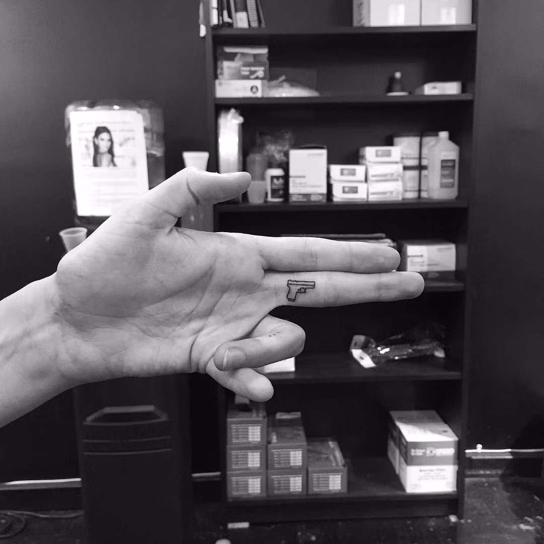 Một hình xăm khẩu súng theo trào lưu xăm Tiny tại ngón tay.