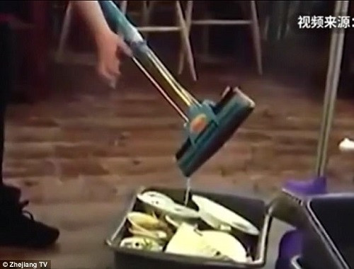 Nữ nhân viên vắt nước giẻ lau vào bát đũa phục vụ khách.