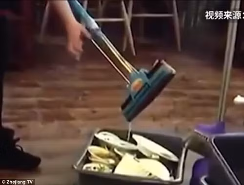 Nữ nhân viên vắt nước giẻ lau vào bát đũa phục vụ khách.