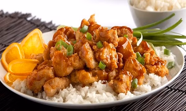 Khi ức gà đã xém mặt cho muối, đường, gừng, quế bột vào chảo, khuấy đều cho mịn. Đổ nước cam vào nấu, khuấy đều tay cho đến khi sôi, cho ức gà trở lại chảo, đậy vung nấu lửa nhỏ khoảng 30 phút. Rắc vỏ cam và cho múi cam vào chảo, nấu thêm 5 phút là được. Ảnh: Toinayangi.