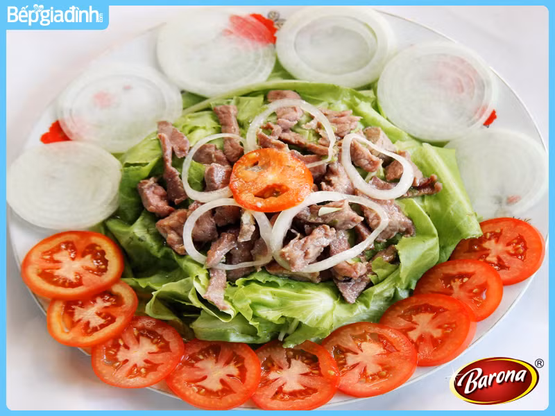 Thịt bò phile xắt mỏng ướp với 1 ít dầu hào, dầu ăn, hạt nêm, tiêu, 1 củ tỏi đập dập 30 phút. Phi thơm tỏi, cho thịt bò vào đảo với lửa lớn. Cho rau xà lách, nước bò vào cùng nước mắm, giấm táo. Cho thịt bò vào trộn đều, tiếp đến cho rau thơm vào trộn, nêm nếm cho vừa miệng. Ảnh: BepGiaDinh.com.