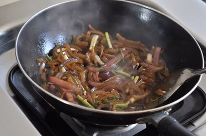 Hành tây xắt múi cau mỏng. Ớt đỏ thái khoanh tròn. Tỏi đập dập và cho vào chảo phi thơm. Sau đó cho hành tây vào xào. Khi các nguyên liệu dậy mùi thơm mới cho bì heo vào đảo đều tay liên tục để bì heo không dính vào nhau. Khi bì heo săn lại, rưới lên chút rượu nấu, đảo đều. Cuối cùng mới nêm xì dầu, nước mắm, tiếp tục đảo đều trong vài phút cho bì đều màu và thấm vị. Ảnh: Wru.