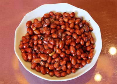 Đun dầu ăn nóng, cho lạc vào rang, đảo đều tay tới khi có mùi thơm, khi chín đổ ra một cái chảo. Lấy hỗn hợp nước mắm, tiêu, đường vào chảo lạc và cũng đảo thật đều tay cho đến khi thấy hạt đậu phộng khô lại là được. Ảnh: PhunuNet.com.