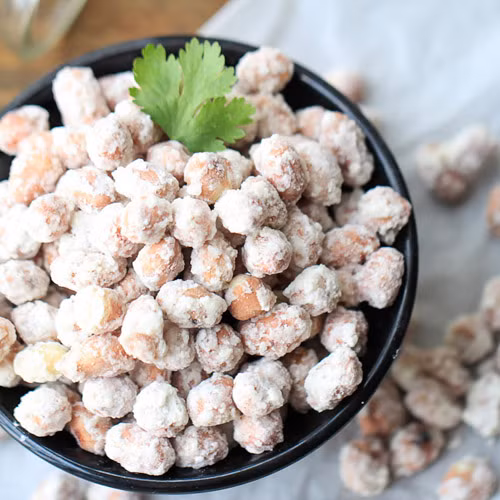 Tiếp theo đổ lạc rang vào, dùng đũa khuấy lên thật đều cho đường bám đều vào từng hạt. Lấy bột bắp đã chuẩn bị sẵn đổ vào chảo lạc đang rang và đảo thật nhanh, đều tay cho bột bọc đều đậu phộng, rồi tắt bếp. Ảnh: Eva.vn.