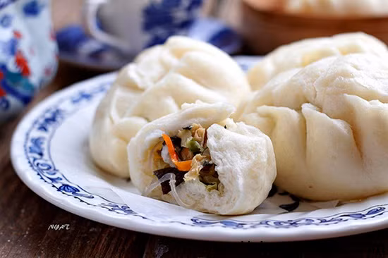 Trong khi chờ bột nở, thái nhỏ cà rốt, củ sắn, nấm ra. Xào cho phần nhân chín lại nhớ nêm gia vị cho vừa ăn. Khi bột nở, bạn vo thành những viên tròn nhỏ, cán dẹp cho nhân vào chính giữa, dùng tay nhấn kín miệng bánh lại. Hấp khoảng 30 phút. Ảnh: hoiquanamthuc.com.