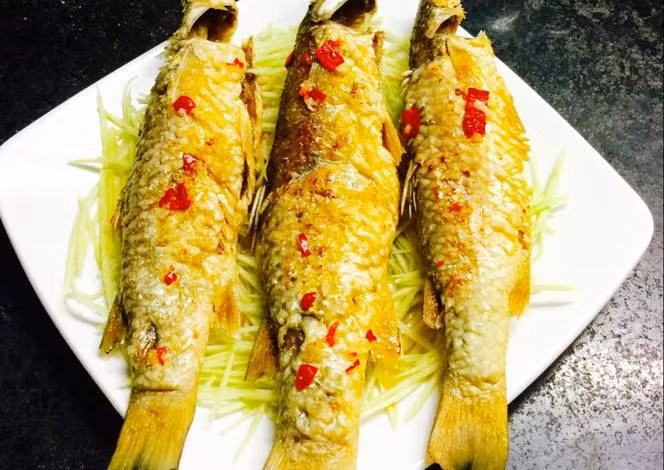 5. Cá đối chiên giòn. Nguyên liệu: Cá đối, nước mắm, muối, tỏi băm, hành khô băm, tiêu xay, ớt, dầu ăn. Cá đối làm sạch để ráo, ướp thêm với tỏi băm, hành khô băm, tiêu xay, hạt nêm, nước mắm cho thấm. Đặt chảo lên bếp, dầu nóng già, cho cá vào rán giòn. Cá ngập trong dầu thì khi rán mới chín thấu và giòn, khi cá chín vàng gắp ra để ráo dầu. Khi ăn chấm với nước mắm, ớt băm nhỏ. Ảnh: cookpad.com.