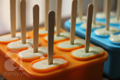 Đánh bông kem tươi và đường đến tạo vân. Chia làm hai phần, một nửa trộn vào hỗn hợp cốm sữa, một nửa trộn vào hỗn hợp cốt dừa. Rót hỗn hợp kem vào khuôn, cắm que. Để khuôn kem vào ngăn đá tủ lạnh 4-6h hoặc qua đêm. Ảnh: Tinybook.net.