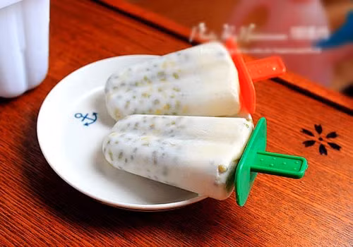 Cho đậu xanh vào máy xay sinh tố, xay nhanh một chút cho phần hạt nát hẳn ra là được. Rót đậu xanh đã xay vào từng chiếc cốc rùi để vào ngăn đá khoảng nửa tiếng thì lấy ra cắm que kem vào. Sau đó, mới cho kem trở lại tủ lạnh để chờ đông hoàn toàn. Ảnh: meovat.net.vn.